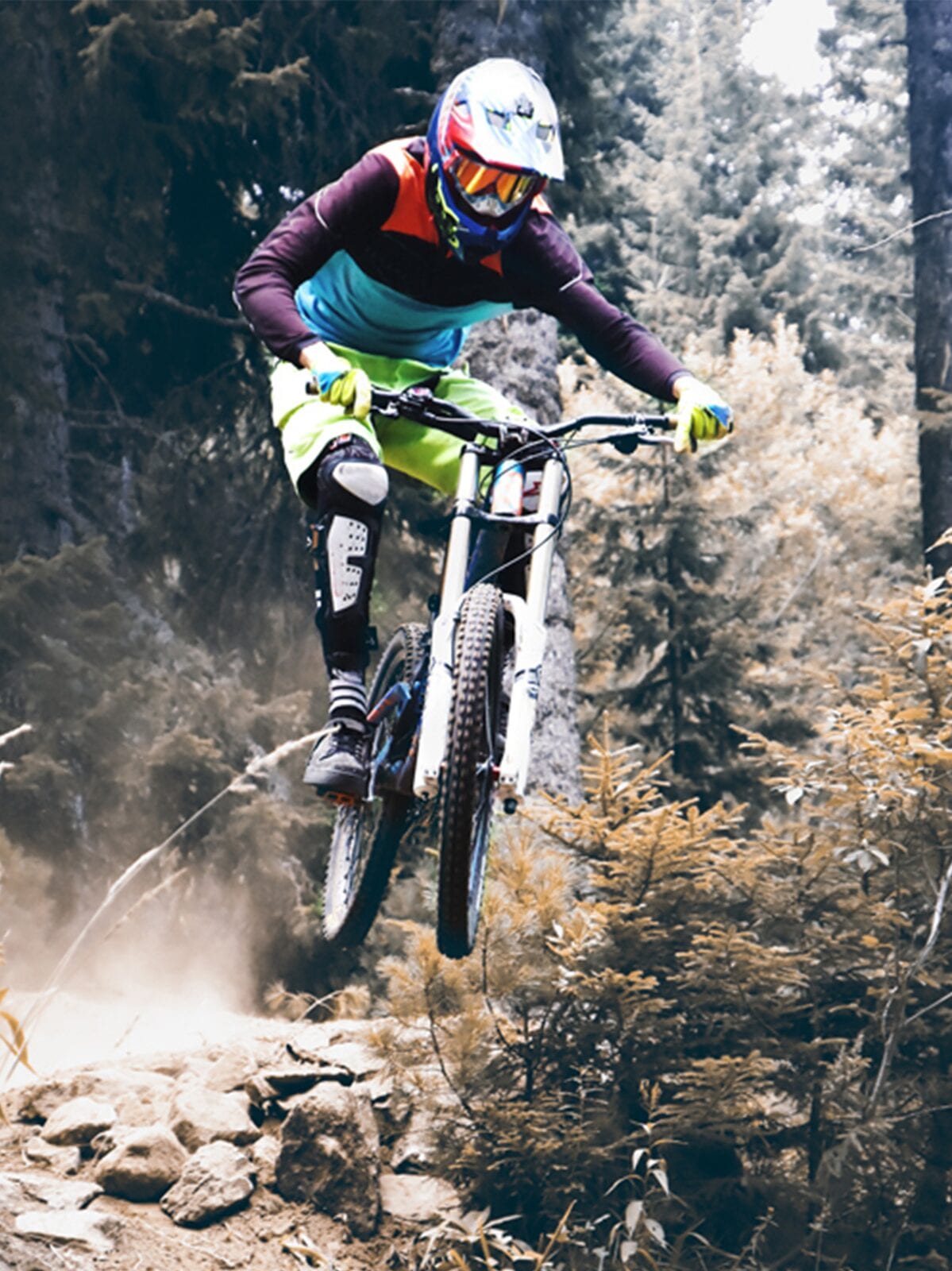 Colourful Biker Jumping off road on hard terrain with a motorbike.