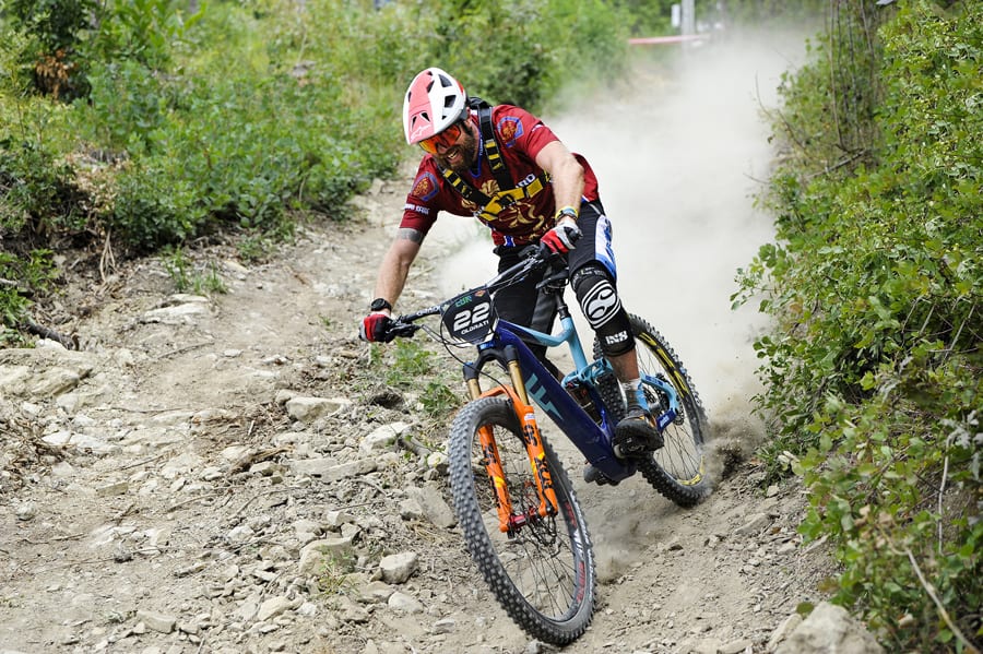 Off road Cyclist riding downhill fast on rocky terrain wearing red top