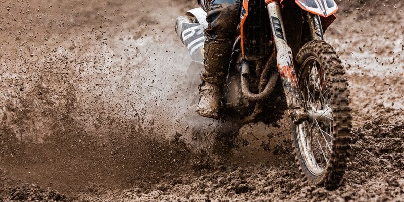 Motocrosser Driving off Road in wet terrain.