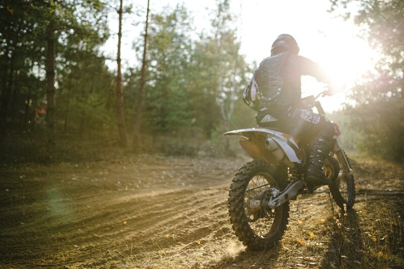 Close up of Off road Biker on a motorbike off road terrain driving hard.